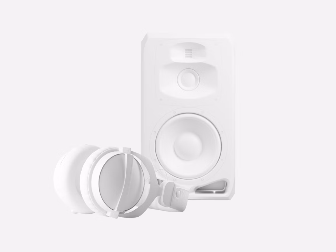 White studio monitor speaker paired with matching over-ear headphones placed in front, minimalist front view on a light gray background for audio production setup.