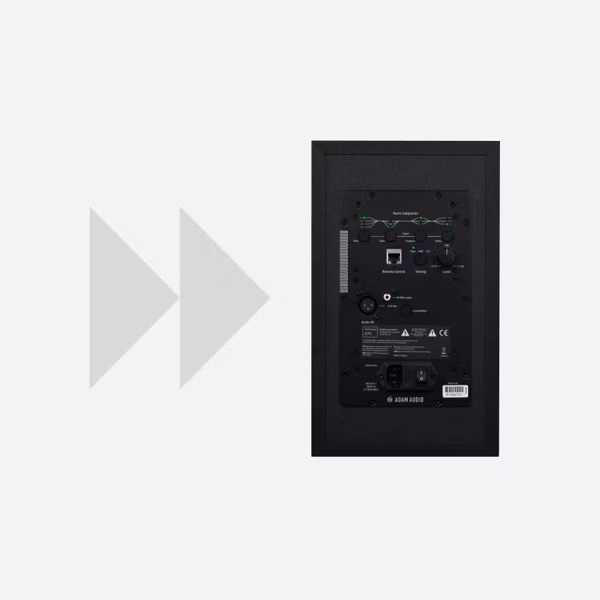 Rear view of an Adam Audio studio monitor showing room adaptation controls, connectivity ports and power inputs, positioned on a light gray background with subtle arrow graphics.
