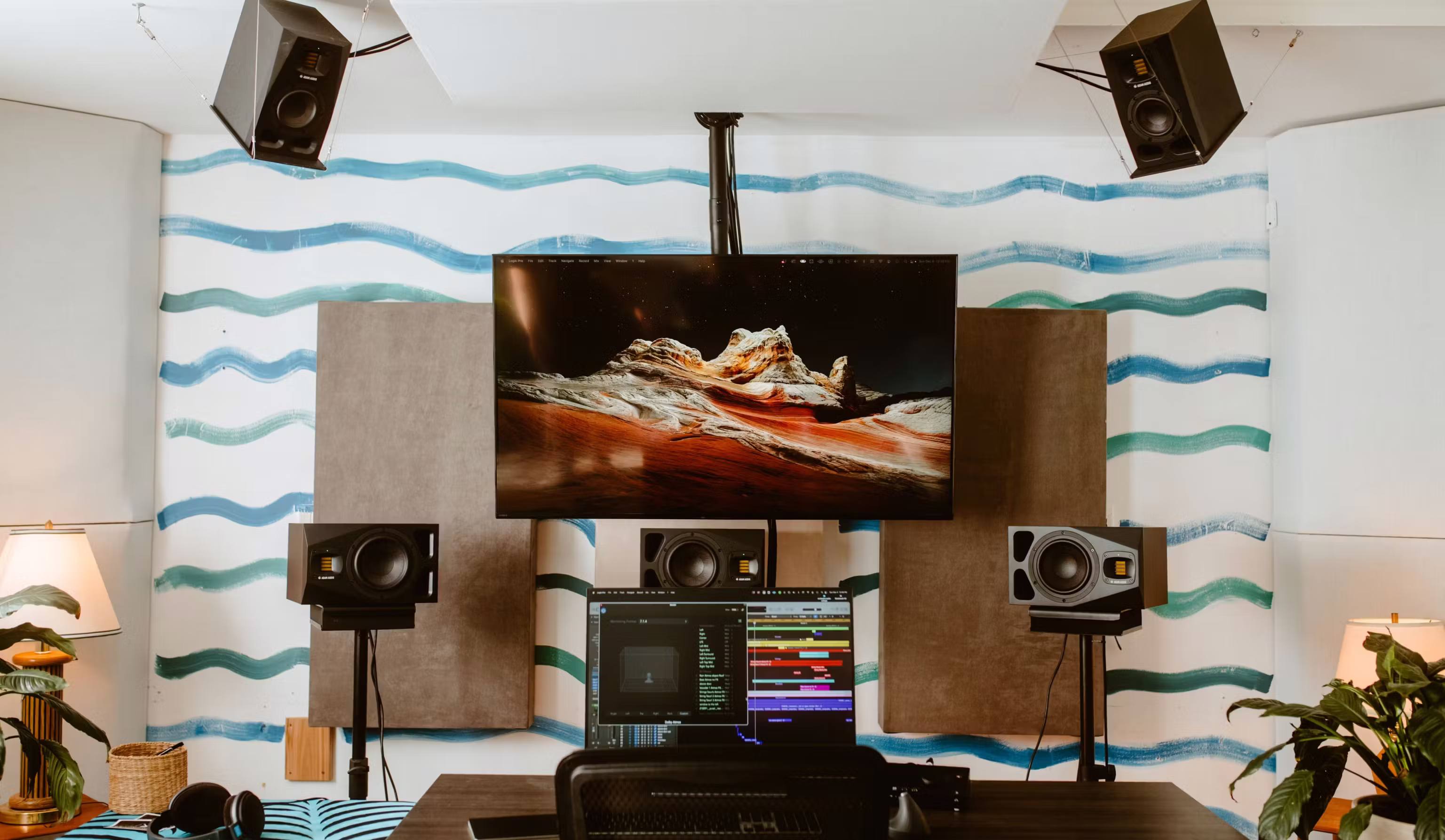 Dolby Atmos studio monitoring room with multiple speakers, acoustic panels, and a dual-screen DAW mixing setup.